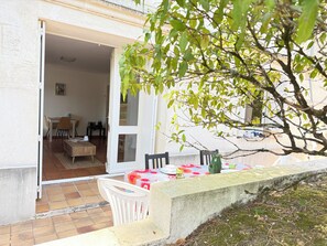 A patio area with a dining table, chairs, and a small table with a vase. - New Listing (Royan)