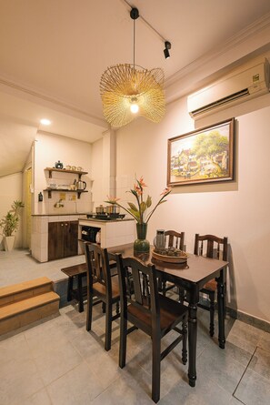 A dining area with a table set for four, surrounded by wooden chairs. A unique hanging light fixture is above the table. - OH Trendy homes Hoan Kiem 3 Bedrooms - Full house 150m2 (Cua Nam)