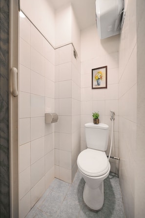 Ein kleines, modernes Badezimmer mit Toilette, Handtrockner und Duschbereich.