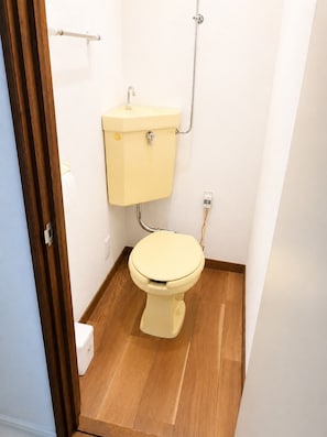 A small bathroom with a toilet, a wooden floor, and a white wall. - New Listing (小樽市)