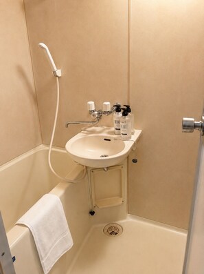 A bathroom with a white sink, a handheld showerhead, and two bottles of lotion. - New Listing (小樽市)