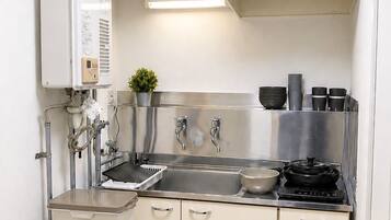 Een kleine keuken met een spoelbak, fornuis en bergkasten.