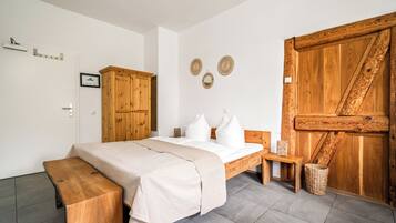 Ein Schlafzimmer mit einem Bett, einem Holzschrank und einer großen Holztür.