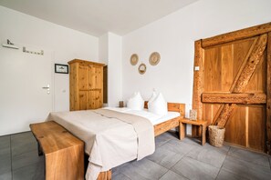 Une chambre à coucher avec un lit, une armoire en bois et une grande porte en bois.