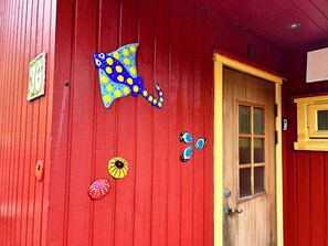 A red wooden building with a door, a window, and decorative fish-shaped stickers on the wall.