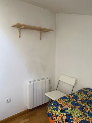 A room with a radiator, a chair, and a bed with a colorful bedspread. - New Listing (Bronchales)