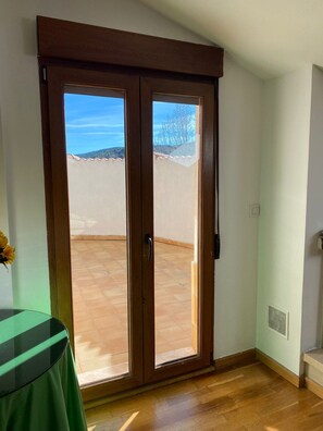 A room with a sliding glass door leading to an outdoor area with a view of a hill and trees. - New Listing (Bronchales)