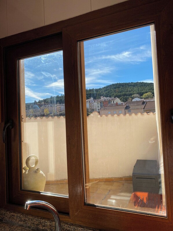 A window with a view of a residential area, a kitchen sink, and a tiled floor.