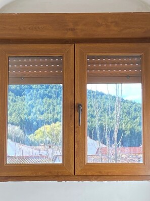 A wooden double door with a view of a forested hillside.