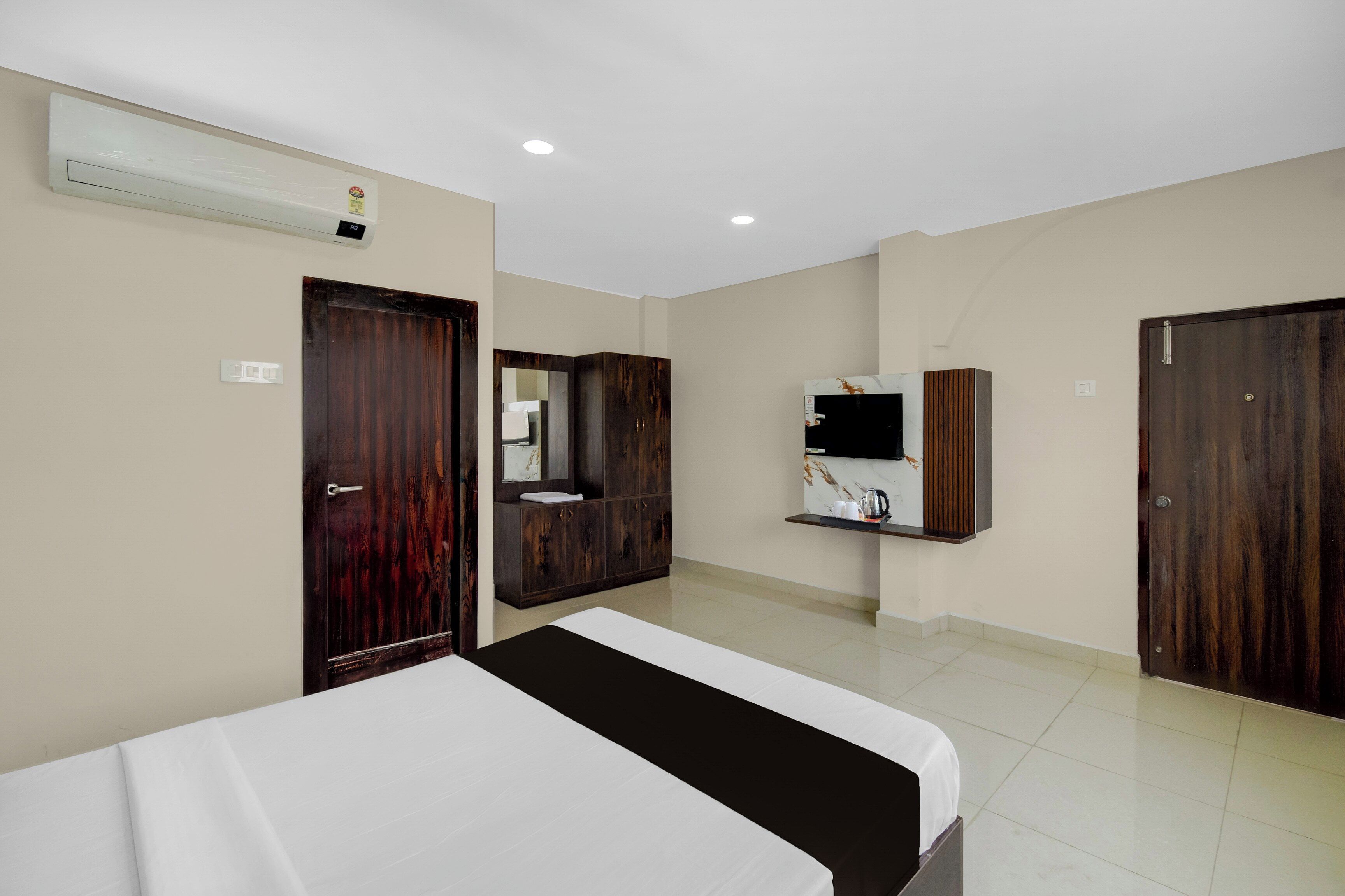 Una habitación de hotel con cama, armario, televisor y aire acondicionado.
