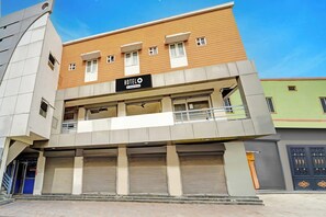 A hotel with a sign indicating it is company-serviced. It has a two-story structure with a flat roof and a balcony on the second floor.
