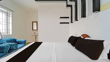 A modern bedroom with a large bed, a blue sofa, and a white wall with black and white geometric patterns.
