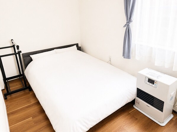 A single bed with a white mattress and a black headboard in a room with wooden flooring. - New Listing (小樽市)