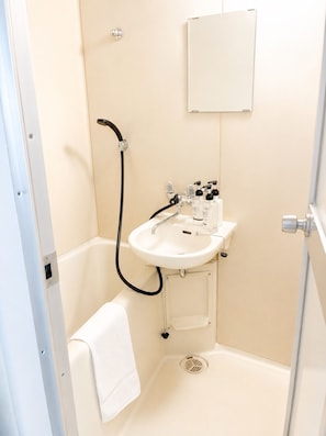 A compact bathroom with a white sink, a handheld showerhead, a towel, and a medicine cabinet. - New Listing (小樽市)