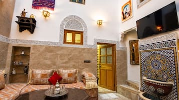 Un interior tradicional marroquí con un sofá, una mesa de centro y un televisor.