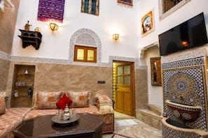 A traditional Moroccan interior with a sofa set, a coffee table, and a television. - House Ismaël Luxrious Fez (Fez)