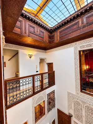A multi-level interior with ornate wooden paneling, a glass ceiling, and a balcony with a wrought iron railing.