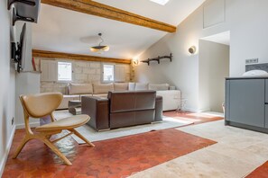 Ein modernes Wohnzimmer mit einer Couch, einem Sessel, einem Couchtisch und einer Küchenzeile mit Schränken und einem Spülbecken.