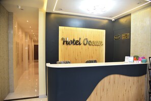 A hotel reception desk with a wooden panel backdrop and a sign that reads 'Hotel Ocean.' - Hotel Ocean Borivali (Mumbai)