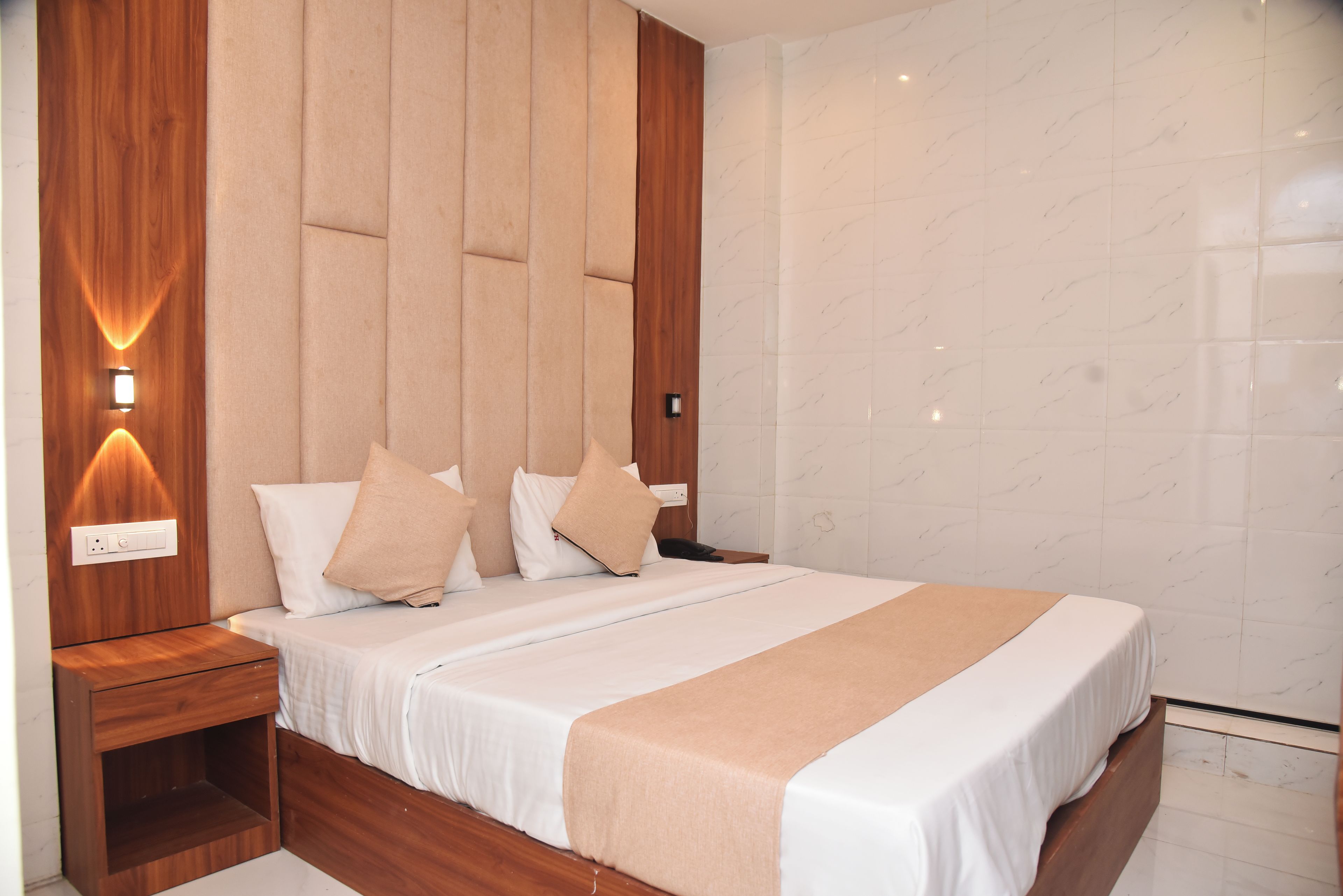 A modern bedroom with a large bed, wooden headboard, and a nightstand.