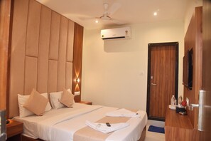 A hotel room with a bed, a ceiling fan, an air conditioning unit, a wooden wardrobe, and a television. - Hotel Ocean Borivali (Mumbai)