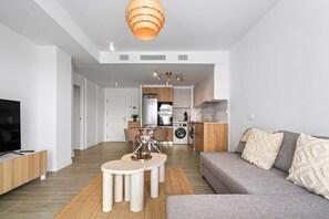 Ett modernt vardagsrum med en grå soffa, ett soffbord och en tv som står på ett träställ.