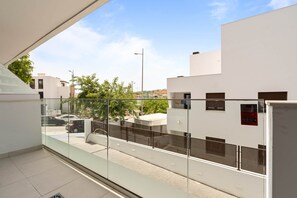 Un edificio moderno con un balcón de vidrio que da a la calle.
