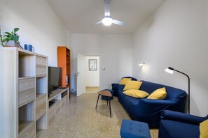 A compact living space with a sofa, a small table, a cabinet with drawers, a ceiling fan, and a radiator. - GuestHost - Ondina Apartment in Downtown Pesaro (Pesaro)