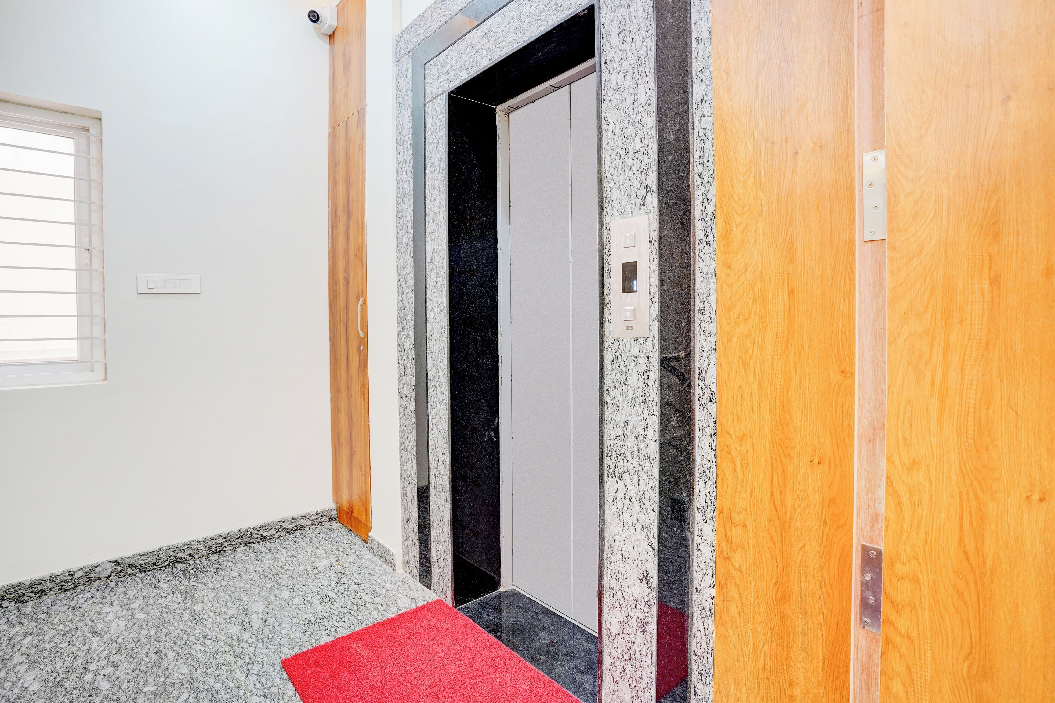 A hallway with a red carpet leading to a door with a marble frame.