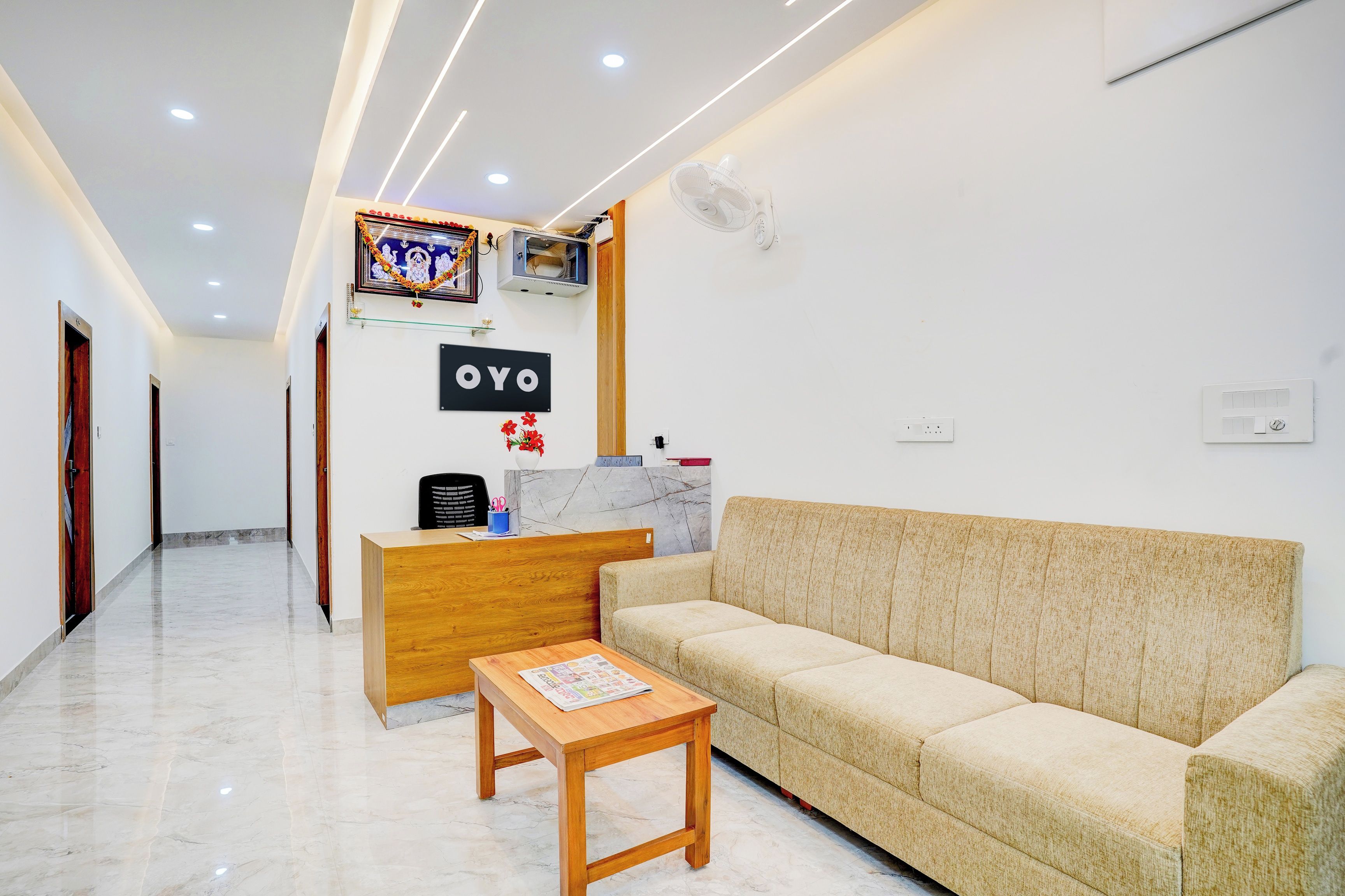 A reception area with a wooden desk, a sofa, and a small table with a newspaper.