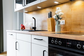 Eine moderne Küche mit Holzarbeitsplatte, einem eingebauten Backofen und einer Edelstahl-Dunstabzugshaube.