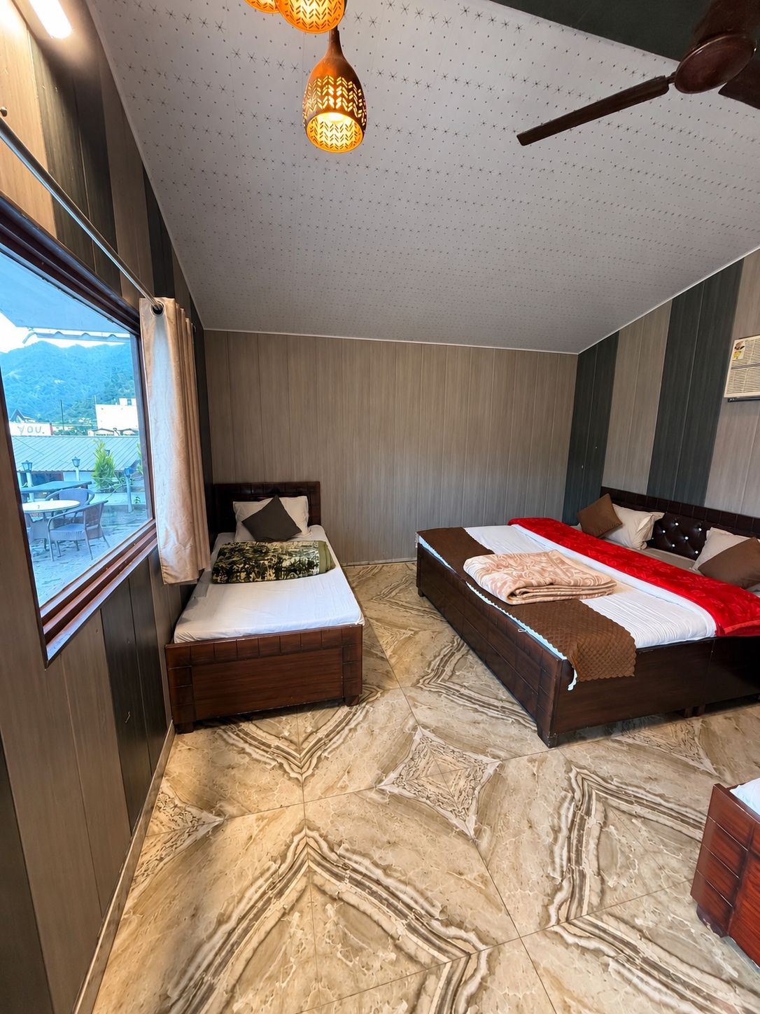 Una camera d'albergo con due letti, vista all'esterno e pavimento a motivi.