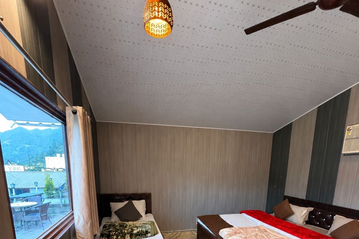 A hotel room with two beds, a view of the outside, and a patterned floor.