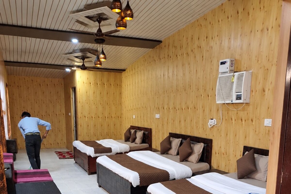 A hotel room with wooden walls, multiple beds, a ceiling fan, and an air conditioning unit.