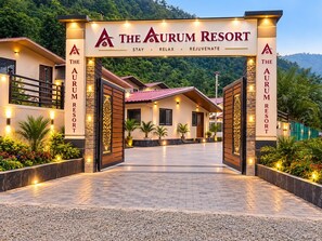 The Aurum Resort entrance with a sign, paved walkway, and surrounding greenery. - The Aurum Resort (Mohan Chatti, Silogi Road)