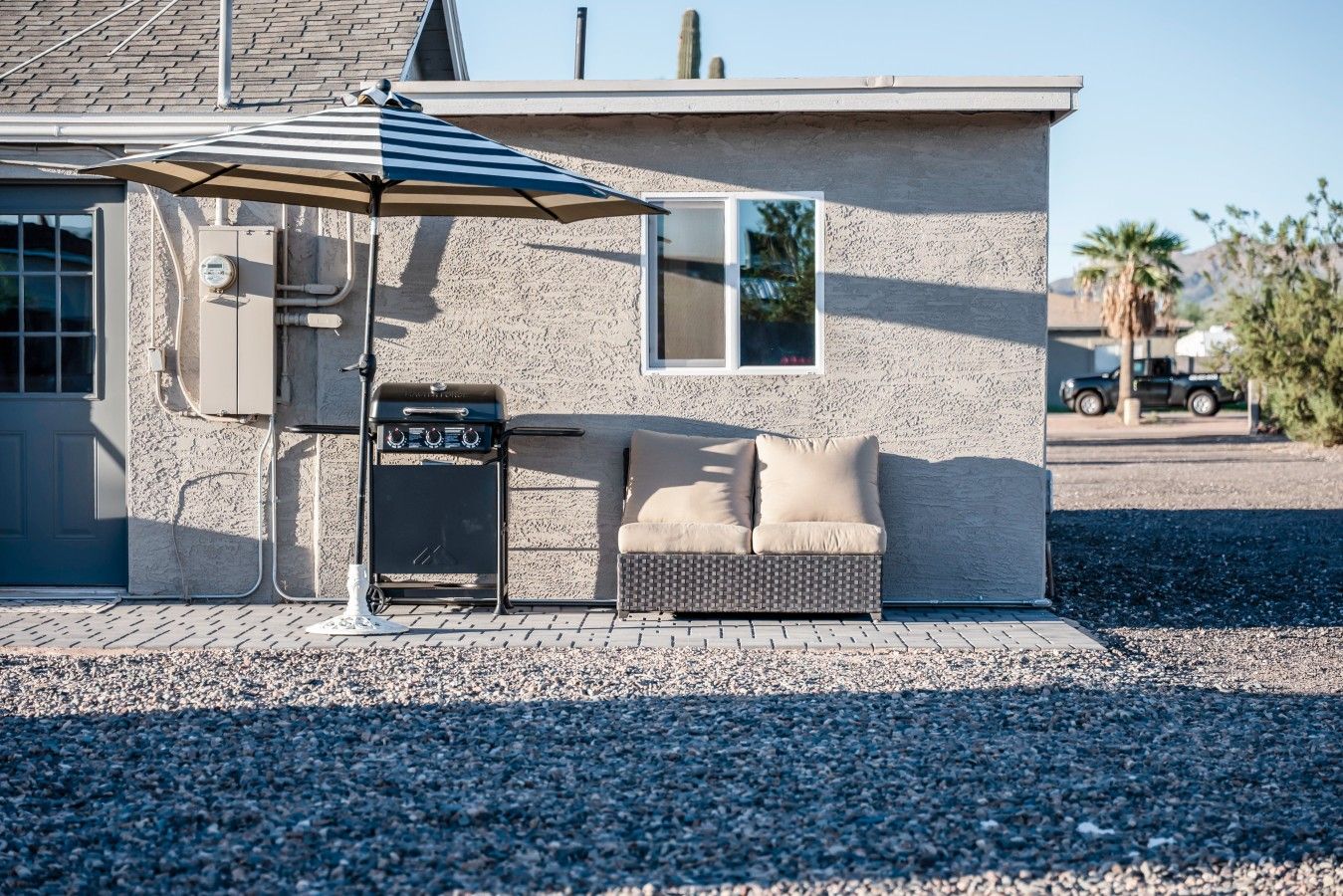 A house with a barbecue grill, a sofa, and an umbrella.