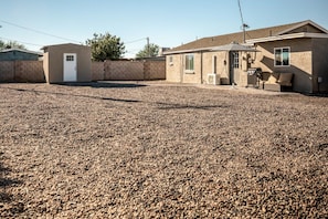 A residential property with a gravel driveway, a small attached garage, and a main house with a covered patio area. - 11319 Home in Apache Junction (Apache Junction)
