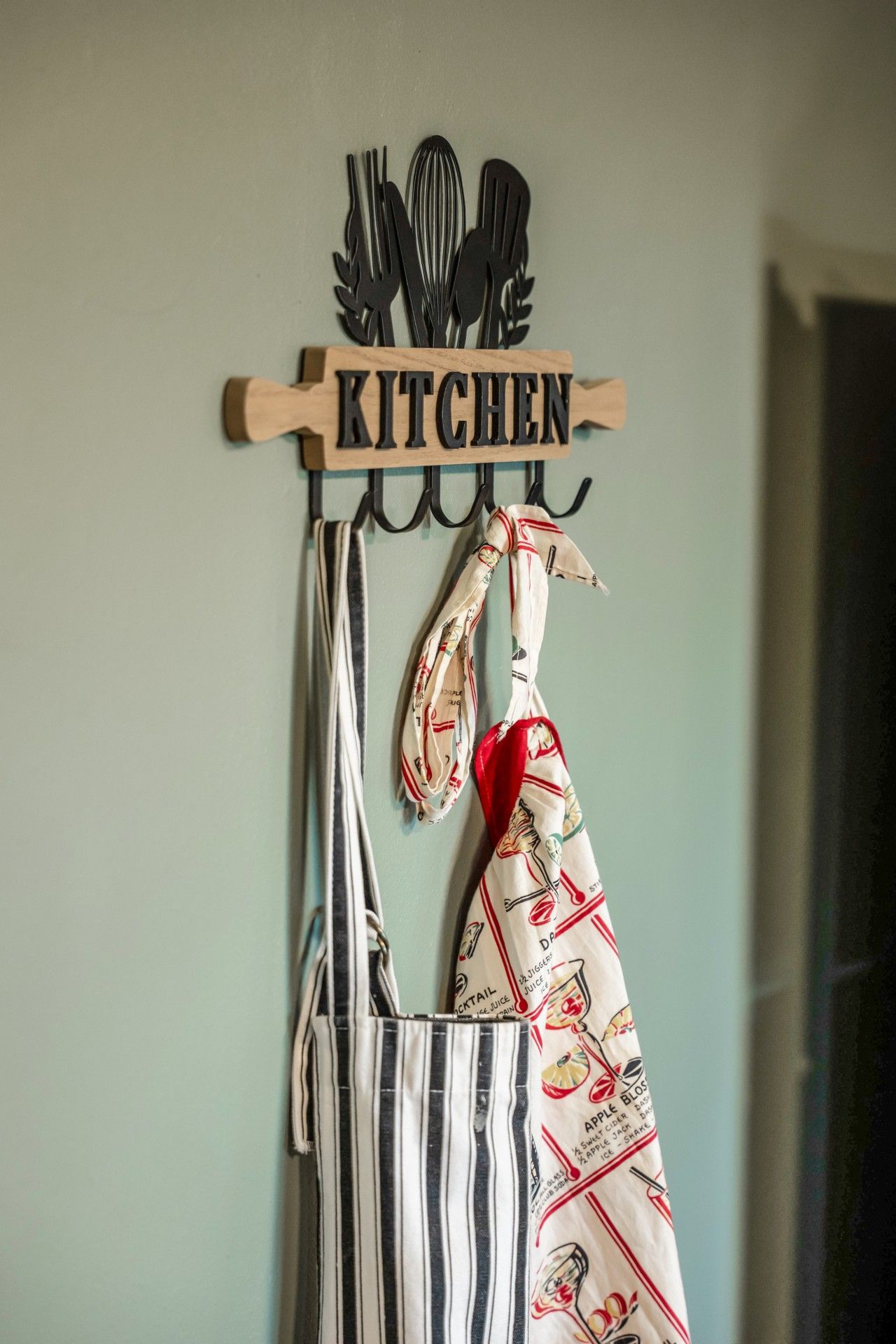 Une enseigne décorative pour la cuisine, avec des ustensiles suspendus en dessous.
