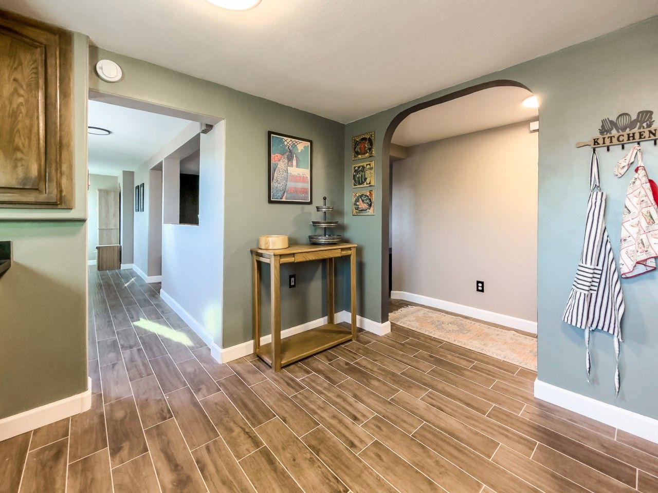 Un couloir doté d’un plancher en bois, d’une console en bois, d’un porte-serviettes mural et d’un tableau encadré accroché au mur.
