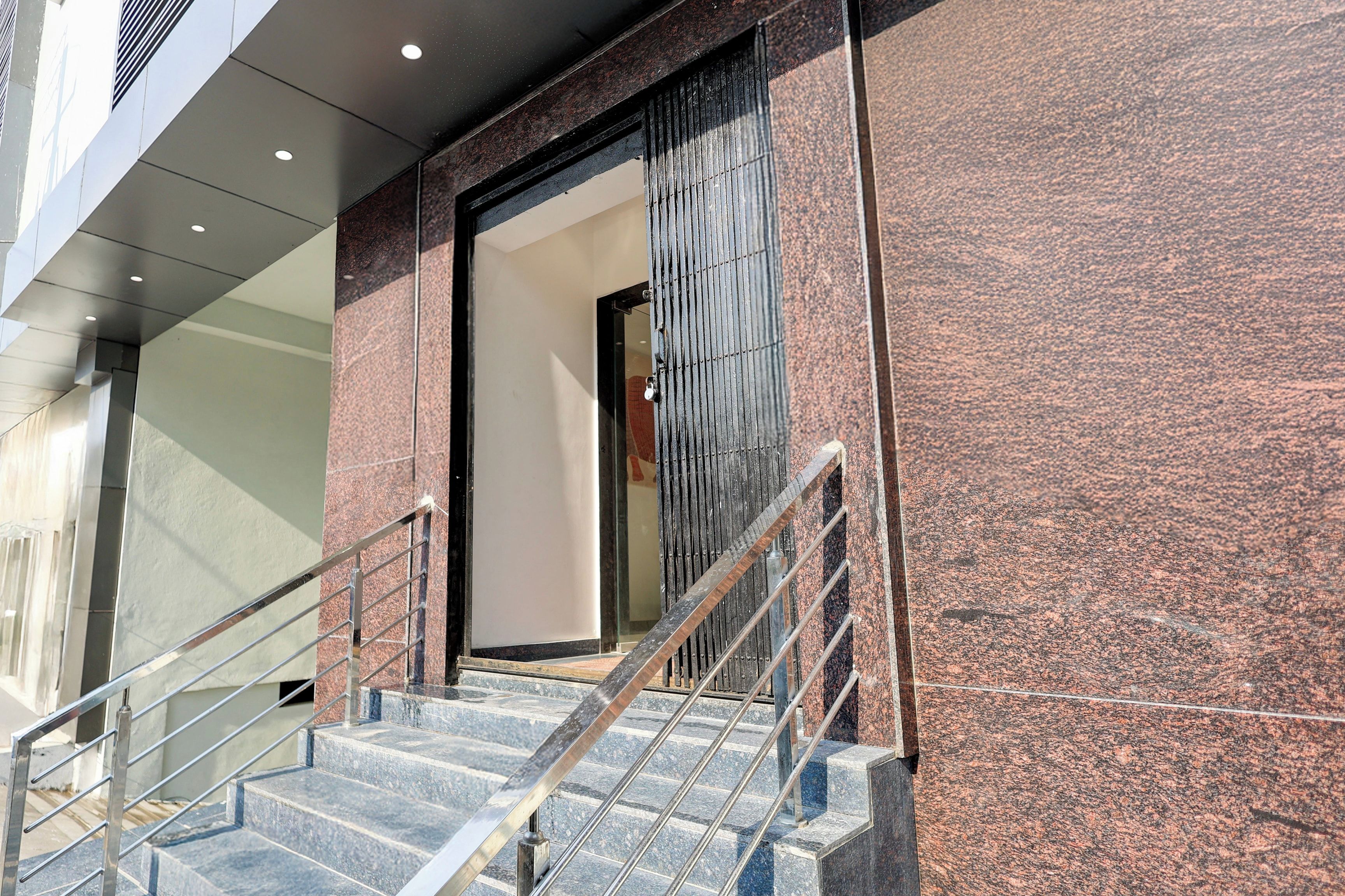 A staircase with metal railings leading to a door with a vertical metal grille.