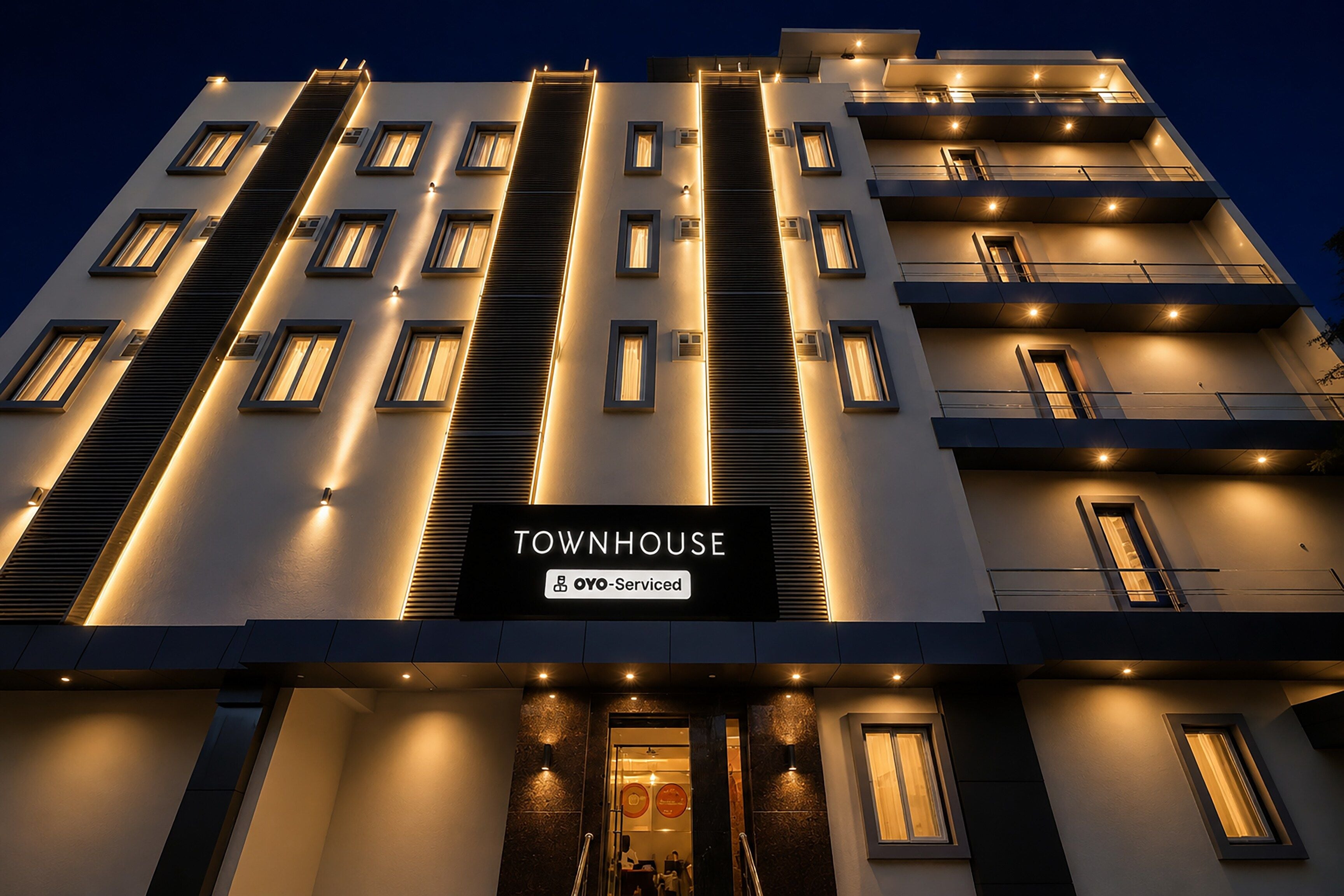 Un edificio de varios pisos con un cartel que dice 'TOWNHOUSE OYO-Service'.