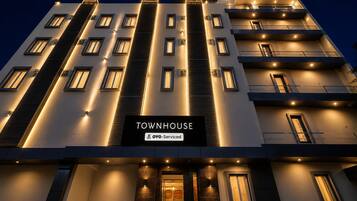 Un edificio de varios pisos con un cartel que dice 'TOWNHOUSE OYO-Service'.