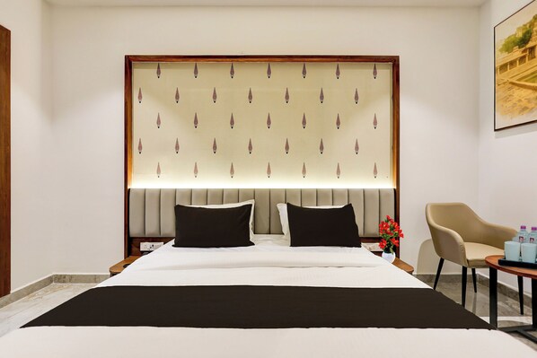 A hotel room with a large bed, two bedside tables, a chair, and a painting on the wall.