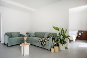 Una sala moderna con un sofá gris, una mesita redonda y una planta en maceta.