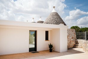 Un edificio moderno con fachada blanca, pared de piedra y valla de metal.