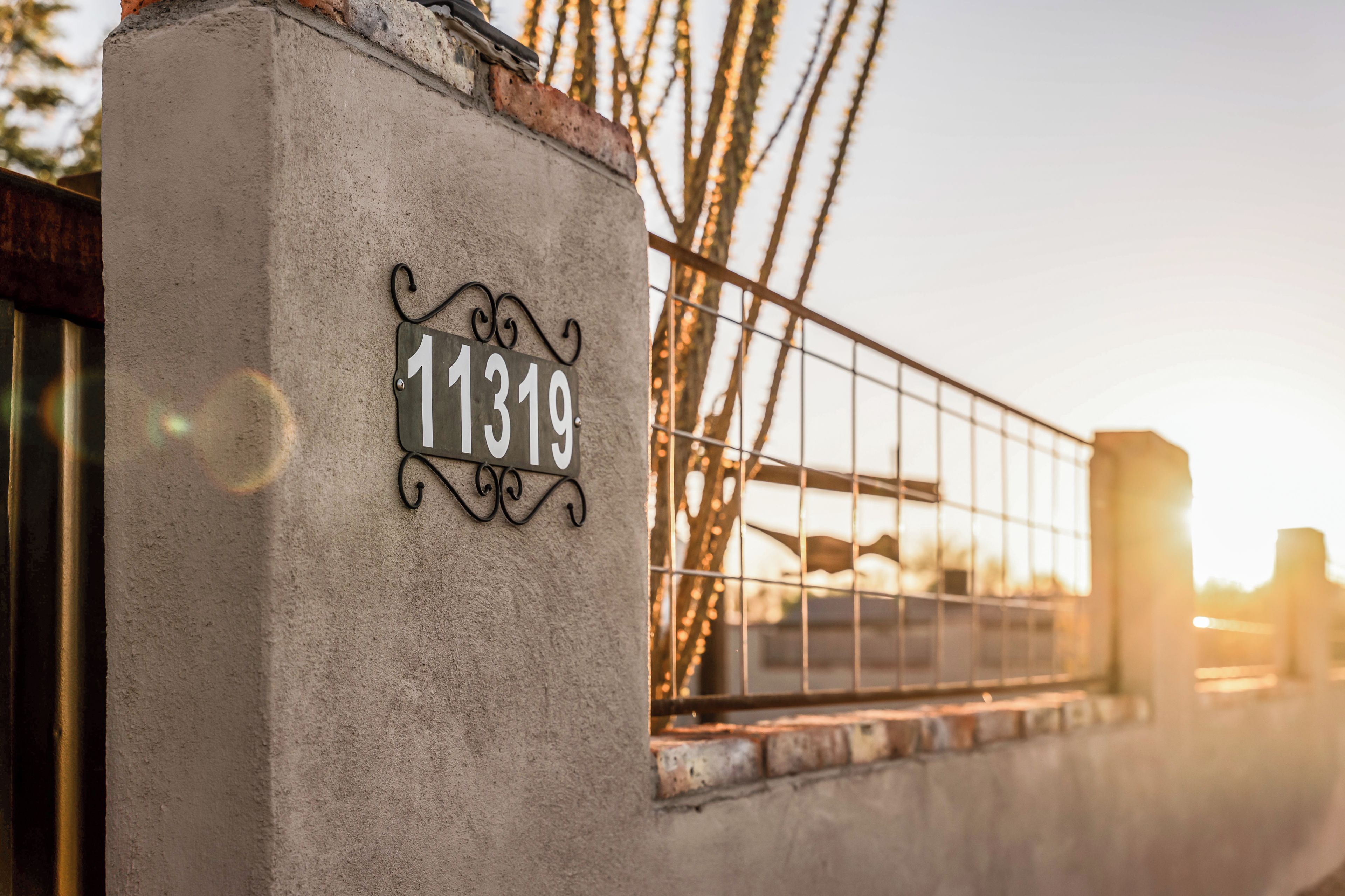 Un mur en béton avec un portail en métal et une plaque indiquant le numéro de la maison.