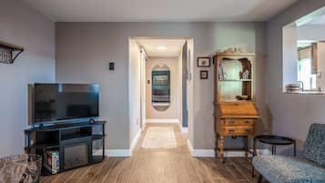 A living room with a television, a wooden cabinet, and a bench.