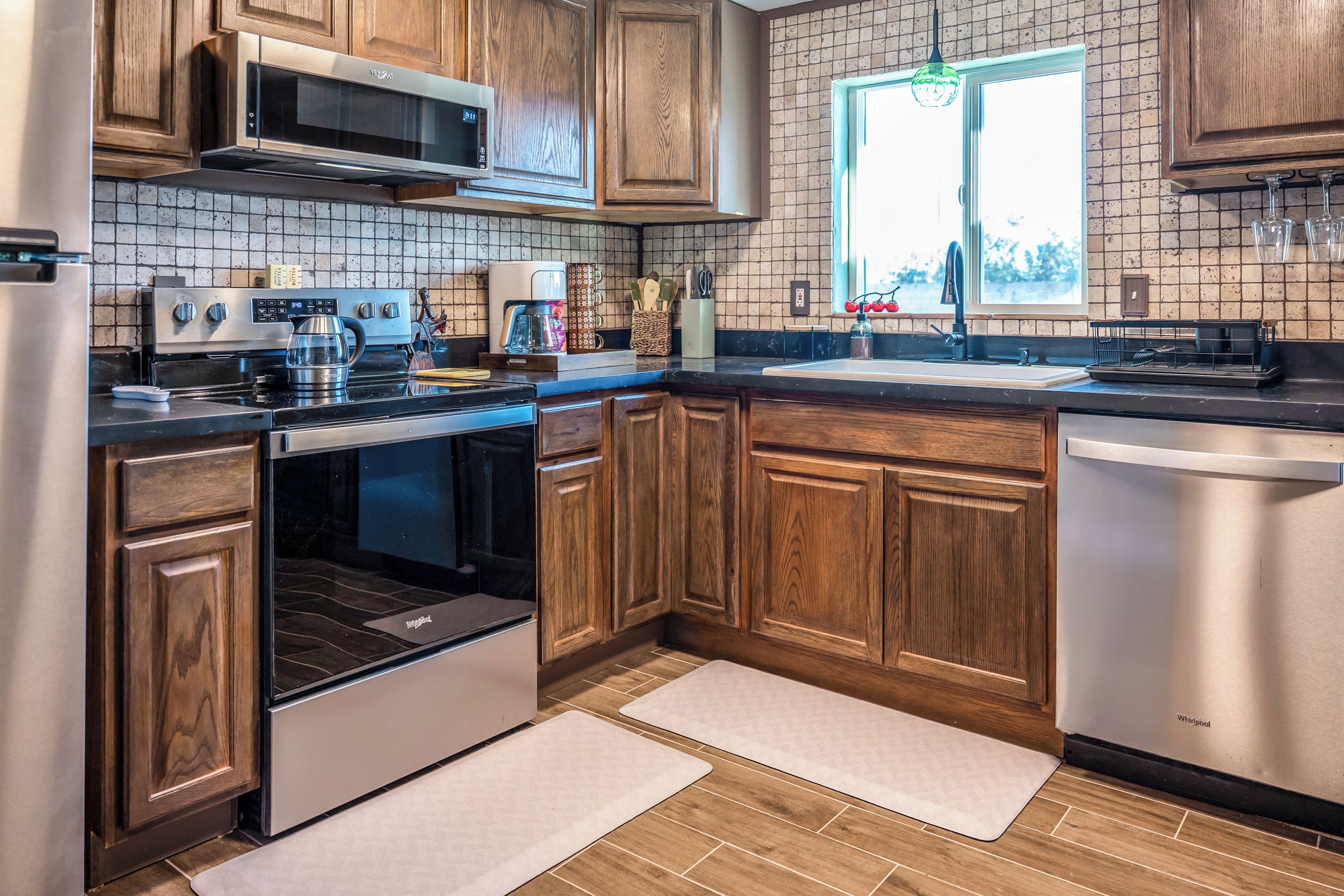 A modern kitchen with wooden cabinets, stainless steel appliances, and a window with a view.