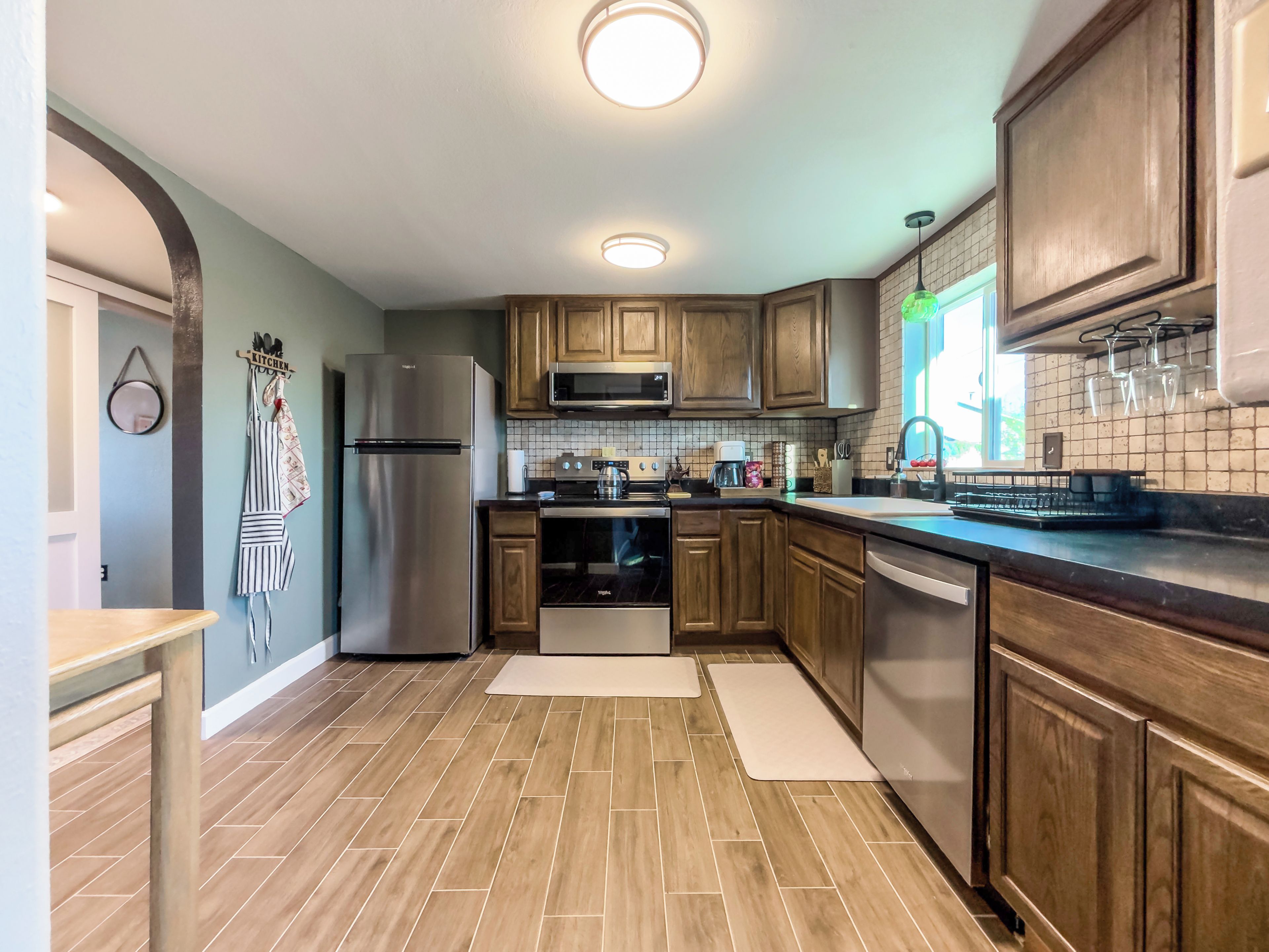 A modern kitchen with wooden cabinets, stainless steel appliances, and a tiled backsplash.