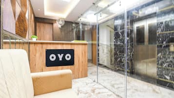 Un área de recepción con un escritorio de madera, un cartel que dice 'OYO' y un piso de mármol.